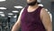 Inspired fat man in headphones walking on gym running track, endurance, health
