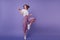 Inspired jocund girl in sneakers dancing on purple background. Gorgeous young female model with dar