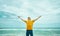 Inspired man enjoying majestic seascape while looking up and raised hands