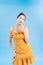 Inspired woman playfully posing on blue background. Amazing pinup lady in short dress enjoying photoshoot