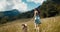 Inspired young adult woman run with bordercollie dog on mountain meadow