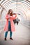 Inspired young woman in pink coat playing a fiddle on the overhead passage