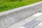 Installation of concrete curbs. Road infrastructure repair. Green grass grows near the paving slabs separated by a concrete curb.