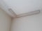 Installation of mouldings on the ceiling of the refurbished room. Fragment of molding, top view of corner placement. Home