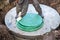 Installation of a septic tank. A worker lowers a manhole cover onto a concrete well