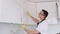 Installation of upper kitchen cabinets. A happy smiling repairman fixing cabinet with screwdriver in kitchen