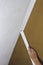 Installing crown molding on ceiling in room with painted wall. Fragment of molding, horizontal view.