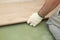 Installing laminate or parquet floor in room, detail on man hands fitting wooden tile, over green foam base