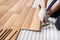 Installing laminated floor, detail on man hands fixing one tile with hammer, over white foam base layer