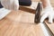 Installing laminated floor, detail on man hands in white gloves, holding hammer over wooden tile, white base layer under