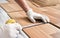 Installing laminated floor, detail on man hands in white gloves holding measuring tape over wooden tile