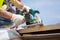 Installing a skylight. Construction Builder Worker use Circular Saw to Cut a Roof Opening for window.