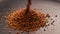 Instant Coffee granules drop in slow motion onto a black surface and form a small pile