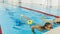 Instructor and child doing exercises in swimming pool. Coach teaches girl to swim