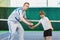 Instructor or coach teaching child how to play tennis on a court indoor