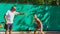 Instructor or coach teaching child how to play tennis on a court indoor