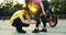 Instructor in a driving school in a yellow t-shirt helps a girl put on protective plates for riding a motorcycle. Knee