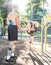 Instructor helping woman stretching at sports ground.