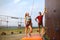 Instructor man guiding pretty slim caucasian woman on rock climbing training wall outdoors. Healthy lifestyle and