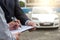 Insurance Agent examine Damaged Car and customer filing signature on Report Claim Form process after accident, Traffic Accident