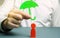 An insurance agent holds a green umbrella over a human figure. Concept of life and health insurance. Unconditional income.