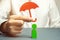 An insurance agent holds a red umbrella over a human figure. Concept of life and health insurance. Unconditional income.