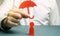 An insurance agent holds a red umbrella over a human figure. Concept of life and health insurance. Unconditional income.