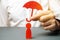 An insurance agent holds a red umbrella over a human figure. Concept of life and health insurance. Unconditional income.