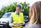 An insurance agent talking to a woman outside on the road after a car accident.