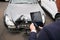 Insurance Loss Adjuster Taking Picture With Digital Tablet Of Damage To Car From Motor Accident