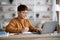 Intelligent asian boy sitting in front of laptop, doing homework