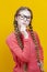 Intelligent Clever Winsome Caucasian Blond Girl In Warm Knitted Sweater Posing with Glasses and Lifted Hands While Thinking And