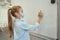 Intelligent little schoolgirl wearing protective mask during coronavirus pandemic writing numbers on board in elementary