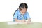Intend little kid girl in school uniform writing on notebook at desk isolated over white background