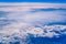 Intense blue sky with white clouds and plane crossing it, seen from above in another plane