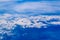 Intense blue sky with white clouds and plane crossing it, seen from above in another plane