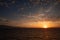 Intense evening sky with glowing cloudscape, ripples on ocean and distant islands