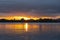 Intense golden sunrise between layer of dark cloudy sky and sea