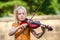 Intense young blonde girl playing violin outdoors