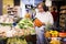 Interested aged woman choosing fresh carrots in supermarket