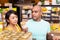 Interested couple reading product label on jar in supermarket