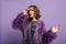 Interested fashionable woman in trendy fluffy outfit looking away with gently smile. Cute young lady in purple clothes