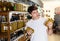 Interested guy choosing pickled olives in glass jars in supermarket