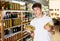 Interested guy choosing pickled olives in glass jars in supermarket