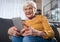 Interested smiling retired woman looking at cellphone at home