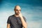 An interesting bald man adjusts his glasses with his hands and looks in surprise at the camera on a blue background