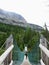 An interesting view of a female hiker looking back as she crosses a suspension bridge high in the remote forests of the rockies