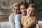 Intergenerational family dynasty of three diverse women cuddle on sofa