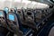 The interior of the aircraft. Empty airplane cabin. Rows of passenger seats with screens in the head restraints