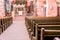 Interior of a beautiful old catholic church from below with marble floor, wooden pews, and light streaming onto altar